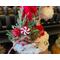 This shows the Christmas arrangement on the elf hat. It includes pine sprigs, a reindeer ornament, red berries, and a faux peppermint candy.